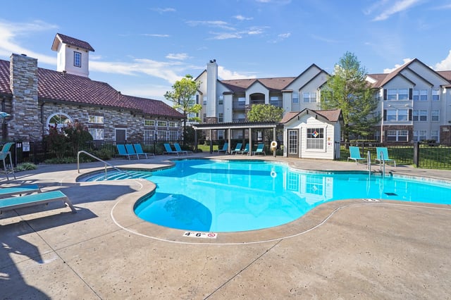 Resort-style swimming pool with lounge chairs and apartment buildings in the background.