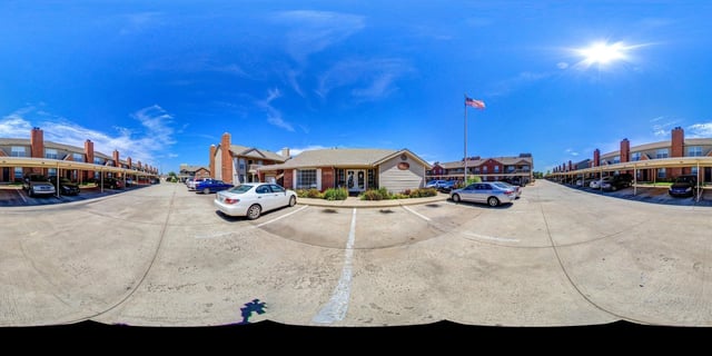 Exterior view of apartment buildings with covered parking and an American flag.