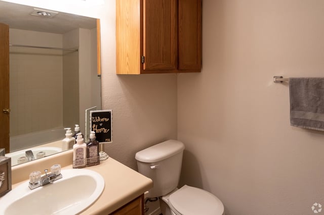 Bathroom with vanity, toilet, and shower. Includes a "welcome home" sign.
