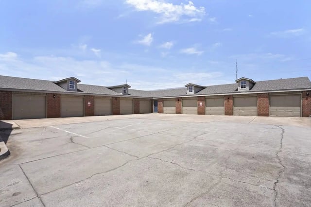 Row of beige garage doors along a brick apartment building exterior.