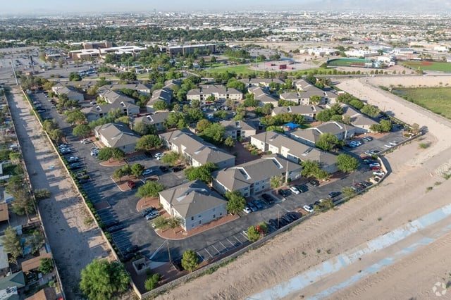 Aerial view of apartment buildings with parking lots and landscaping.