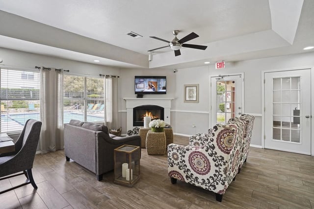 Community lounge with fireplace and view of pool area.