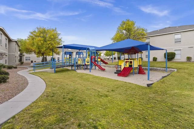 Playground with blue shade canopies and colorful equipment in a residential courtyard.