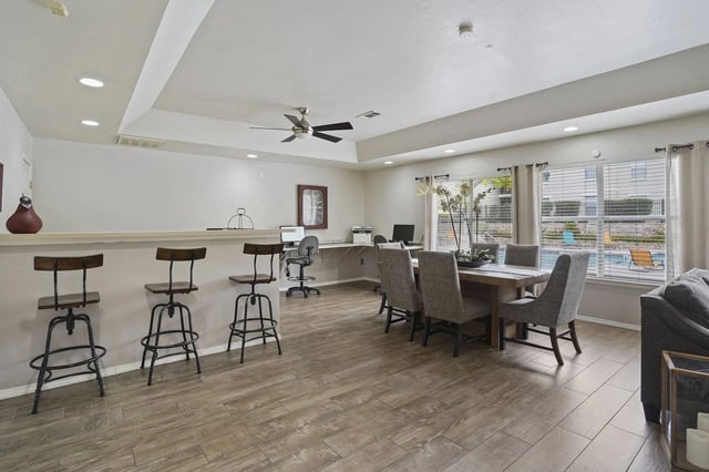 Communal dining area with a table and chairs, bar seating, and a view of the pool.