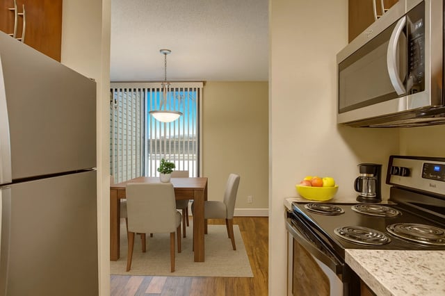 Kitchen with stainless steel appliances and dining area with table and chairs.