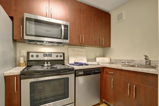 Modern kitchen with stainless steel appliances and dark wood cabinets.