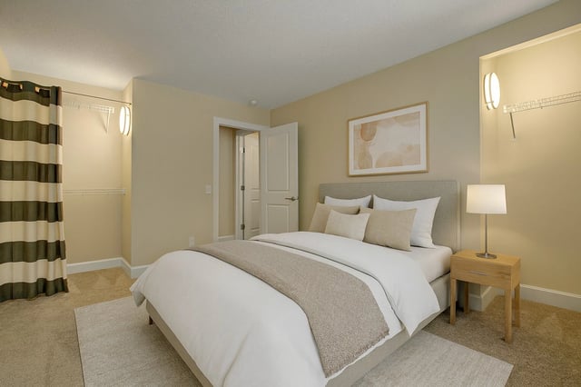 Bedroom with a queen-size bed, nightstand, lamp, closet, and artwork.