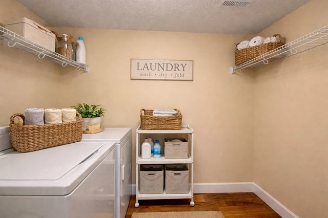 Laundry room with a washer, dryer, shelving, and laundry supplies.