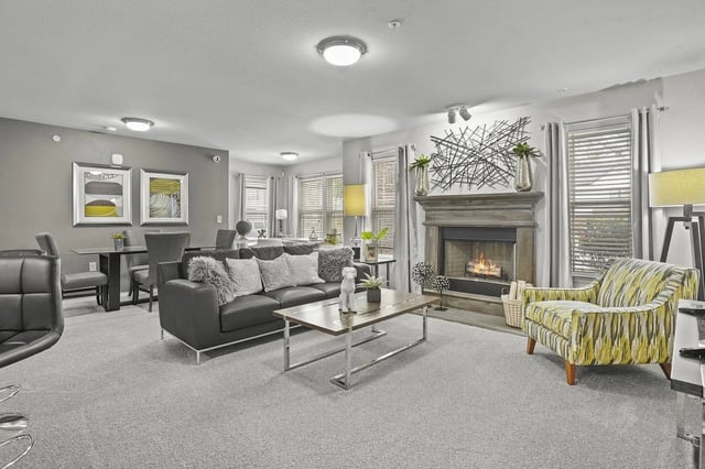 Spacious community lounge with a sofa, armchairs, coffee table, and a fireplace.