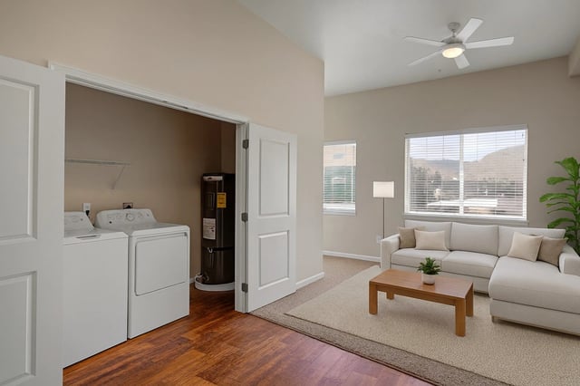 Living area with sectional sofa and coffee table next to a laundry room with washer and dryer.