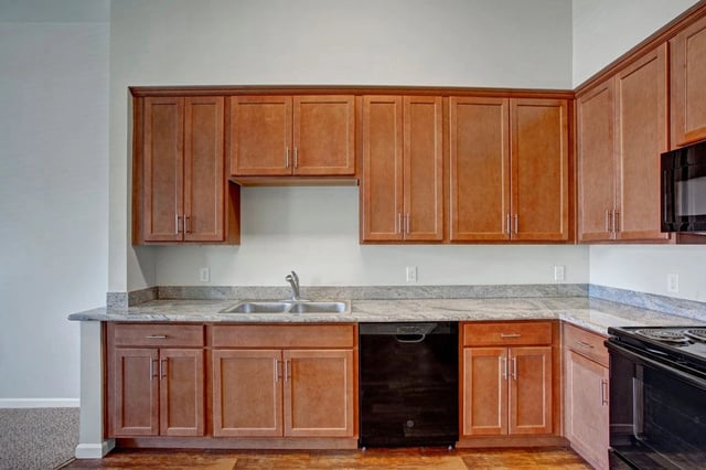 Modern kitchen with wooden cabinets, granite countertops, and stainless steel sink.