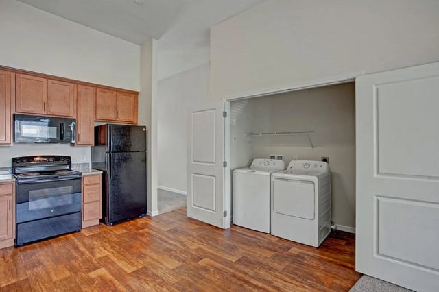 Kitchen with wood cabinets, black appliances, and in-unit washer and dryer.