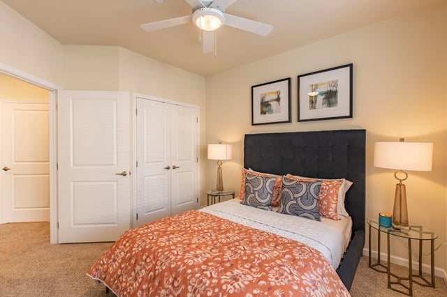 Bedroom with a king-size bed, nightstands, a ceiling fan, and double doors leading to a closet and hallway.