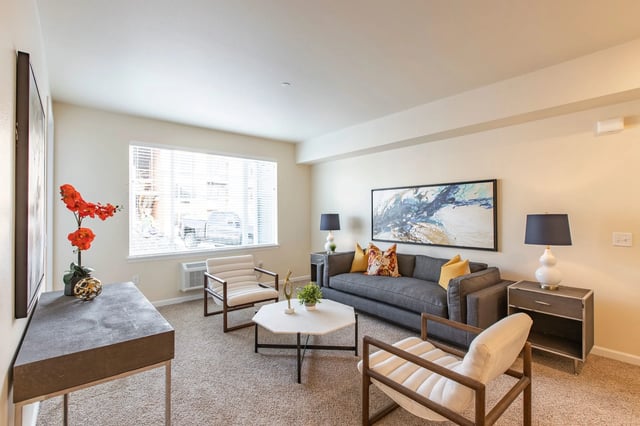 Living room with gray sofa, accent chairs, coffee table, and artwork.