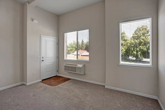 Interior view of apartment entrance with door, air conditioner, and window.