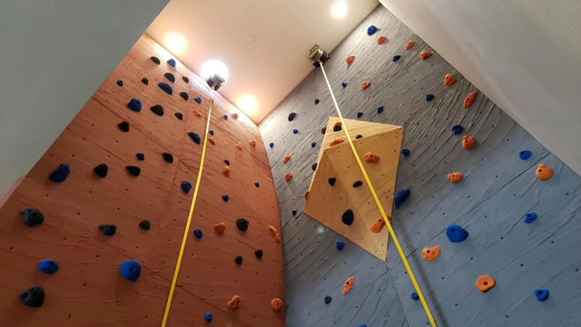 Indoor climbing wall with colorful holds and safety ropes.
