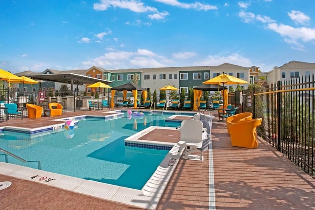Resort-style pool with lounge chairs and umbrellas.