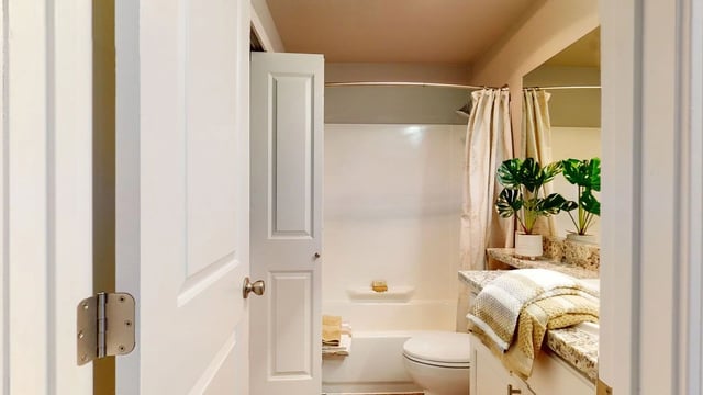 Modern bathroom with a toilet, bathtub, and vanity.