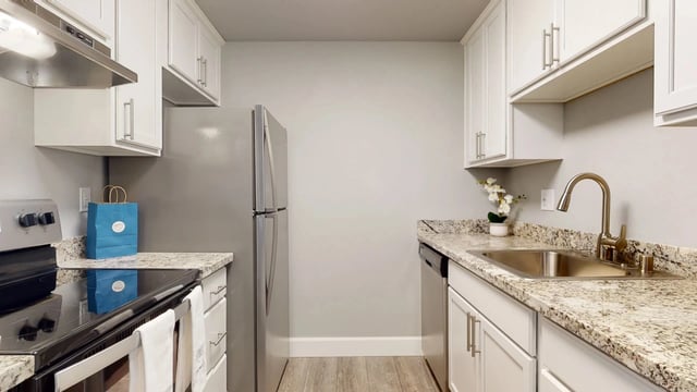 Modern kitchen with white cabinets, granite countertops, stainless steel appliances, and a double-door refrigerator.