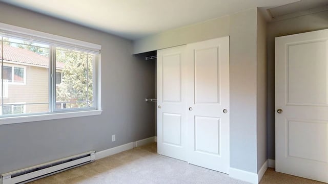 Bedroom closet doors and window in a vacant apartment.