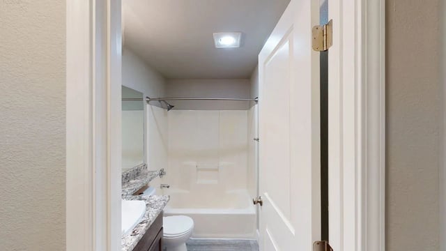 View of a clean and modern bathroom with a vanity, toilet, and bathtub/shower combination.