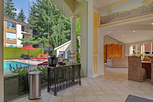 Outdoor swimming pool with lounge chairs and umbrellas, adjacent to apartment buildings.