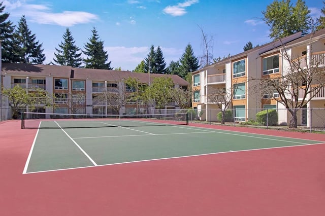 Tennis court with apartment buildings in the background.