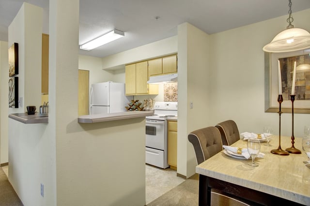 Kitchen and dining area with white appliances and a table set for dinner.