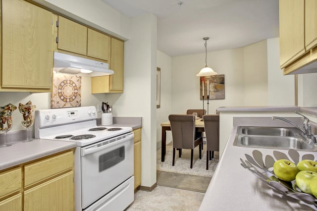 Modern kitchen with light wood cabinets, white oven, and double sink.