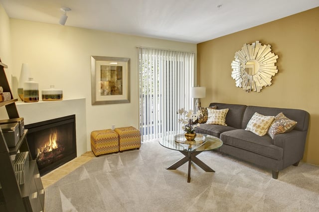 Living room with a fireplace, sofa, coffee table, and decorative mirror.