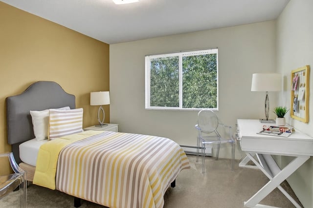 Bedroom with a queen-size bed, a desk, and a window.