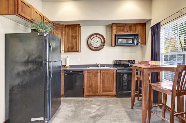 Kitchen with black appliances, wooden cabinets, and a dining table.