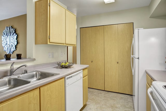 Kitchen with wood cabinets, double sink, dishwasher, and refrigerator.