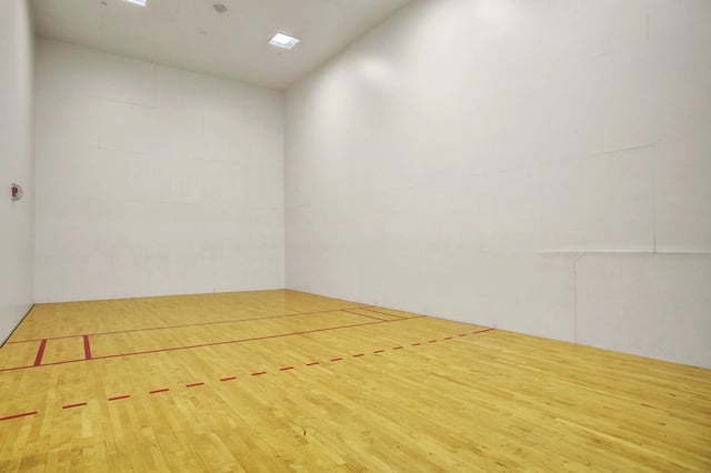 Indoor racquetball court with wooden floor and white walls.