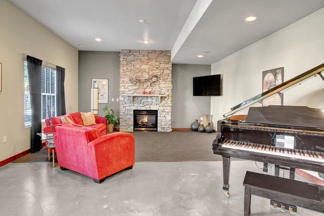 Community lounge with fireplace, grand piano, and seating.