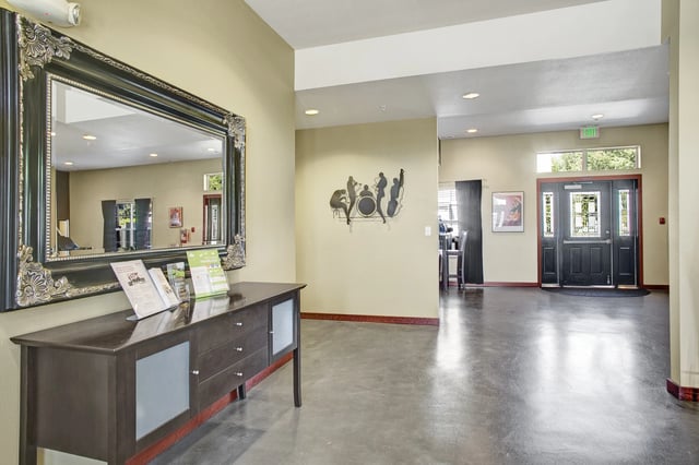 Spacious lobby with a large ornate mirror, console table, and double doors leading outside.