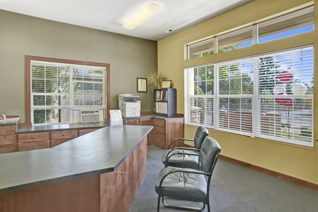Reception desk and waiting area with chairs, printer, and bookshelf.