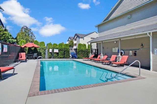 Outdoor swimming pool with lounge chairs and umbrellas.
