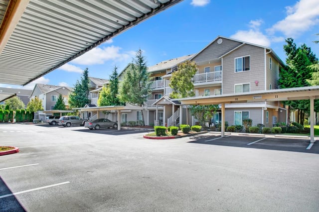 Exterior view of apartment buildings with covered parking and manicured landscaping.