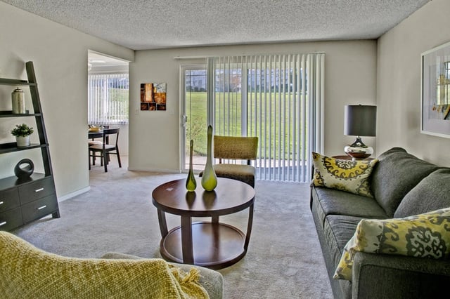 Living room with a couch, coffee table, and sliding glass doors leading to a yard.