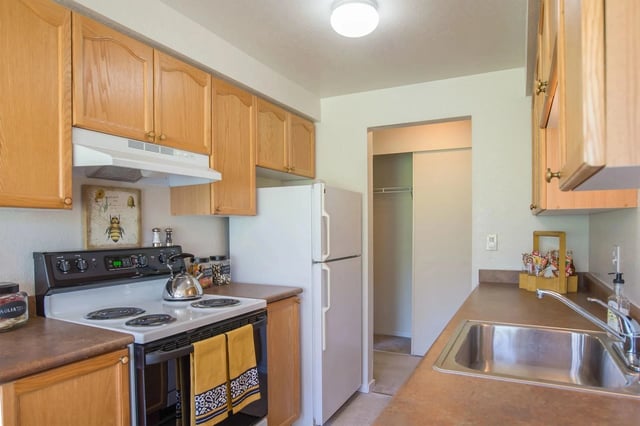 Kitchen with oak cabinets, white stove, and stainless steel sink.