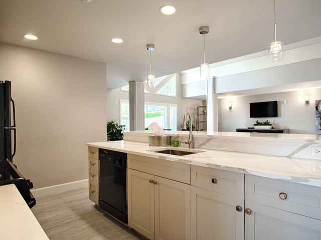 Modern kitchen with white quartz countertops and stainless steel appliances.
