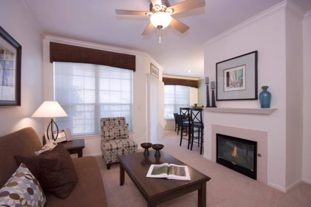 Living room with a sofa, armchair, coffee table, fireplace, and ceiling fan.