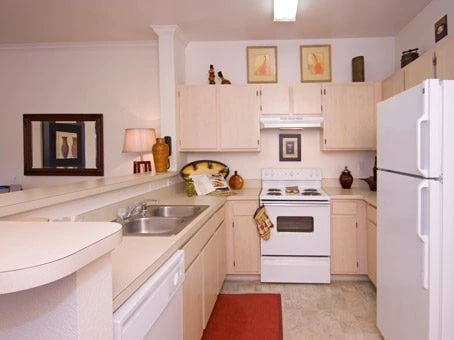 Kitchen with white appliances, cabinets, and countertops. Features a sink, stove, and refrigerator.