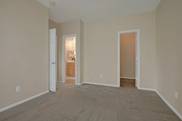 Empty bedroom with doorways to bathroom and closet.