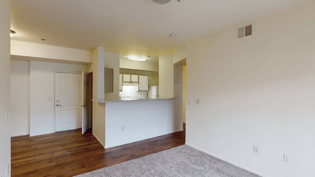 Empty apartment living room and kitchen area with a breakfast bar.