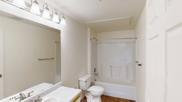 A clean and bright bathroom with a vanity, toilet, and bathtub.