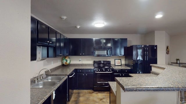 Modern kitchen with dark cabinets, granite countertops, and stainless steel sink.