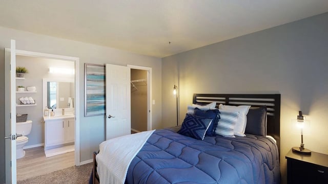 Bedroom with a queen-size bed and a view into the bathroom.