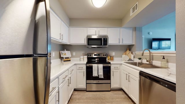 Modern kitchen with stainless steel appliances and white cabinets.